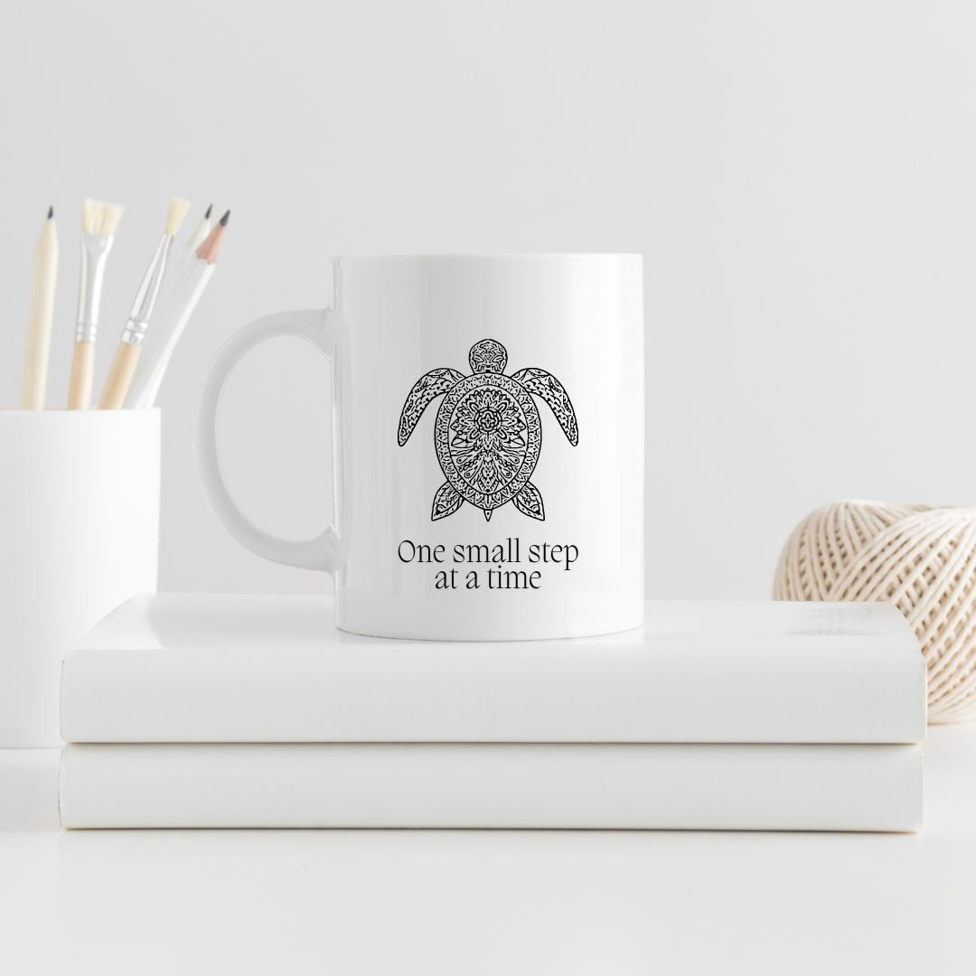 Embrace the journey with this motivational 11-ounce ceramic mug. The mandala pattern wraps around the mug, and a serene turtle image graces both sides. Made from premium quality white ceramic, it’s microwave and dishwasher-safe. Whether you’re sipping coffee, tea, or hot cocoa, let this mug remind you that progress happens one step at a time.